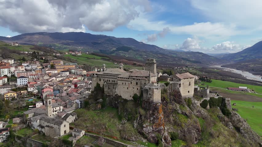 Majestic medieva Bardil fortress castle perched atop a hill overlooking a charming Italian village and scenic rolling landscape in Parma Italy in Ceno Valleynear the Apennines ridge, drone orbiting