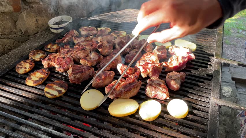 Chicken pork meat and vegetables potatoes on grill, man cooks food meal on rostil