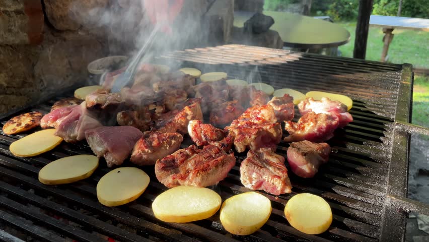 Chicken pork meat and vegetables potatoes on grill, man cooks food meal on rostil