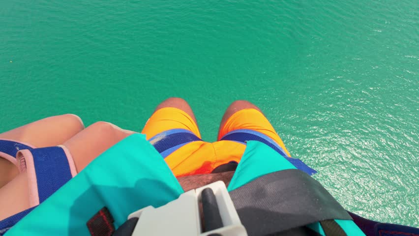 First Person Parasailing. Legs above the seawater while parasailing.