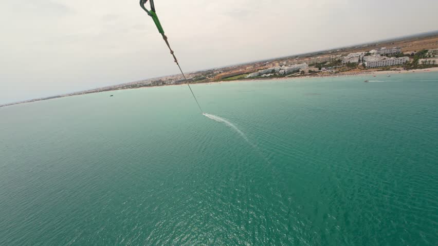 A hand pointing while parasailing above the seawater