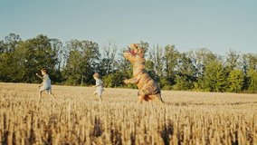 Funny scene of children running across dry meadow while person dressed as giant T Rex Tyrannosaurus dinosaur playfully chases them on bright summer day. - Powered by Shutterstock - Get 15% off with code: PIKWIZARD15