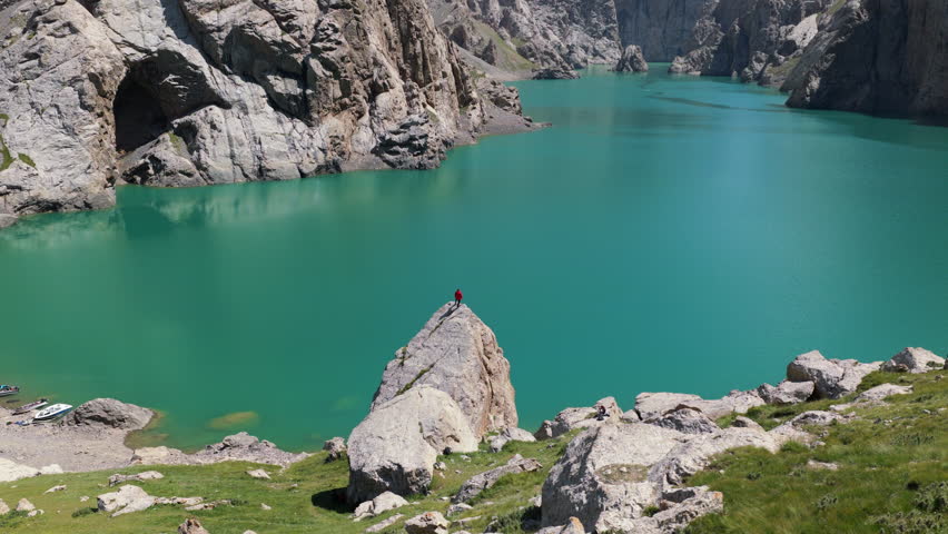 Aerial View Of A Hiker Standing On A Rock In Kol-Suu Alpine Lake In Kyrgyzstan.