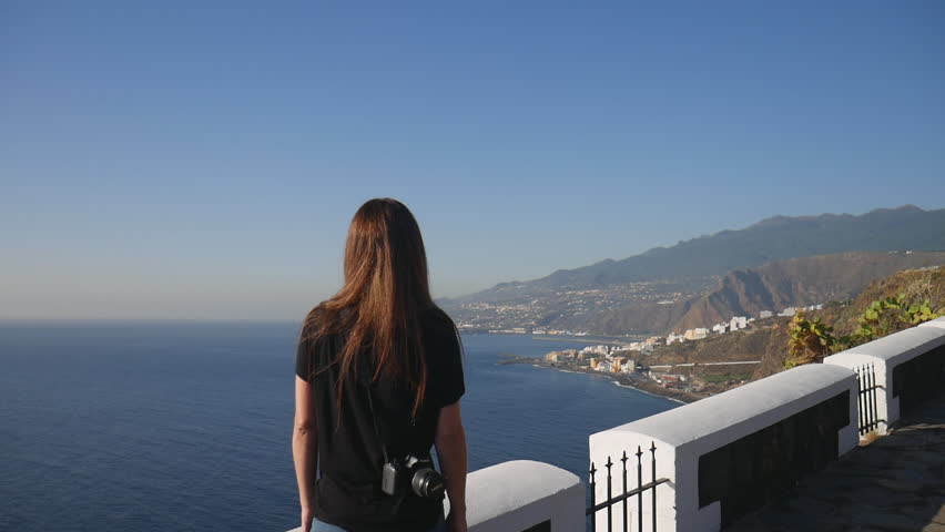 Young woman with a camera enjoying the scenic ocean view on a sunny day in La Palma, Canary Islands