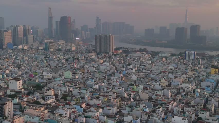 A series of drone clips capturing the winding Saigon River as it flows through the dense urban landscape of Ho Chi Minh City, Vietnam, at sunrise. The footage showcases the city's unique blend of natu