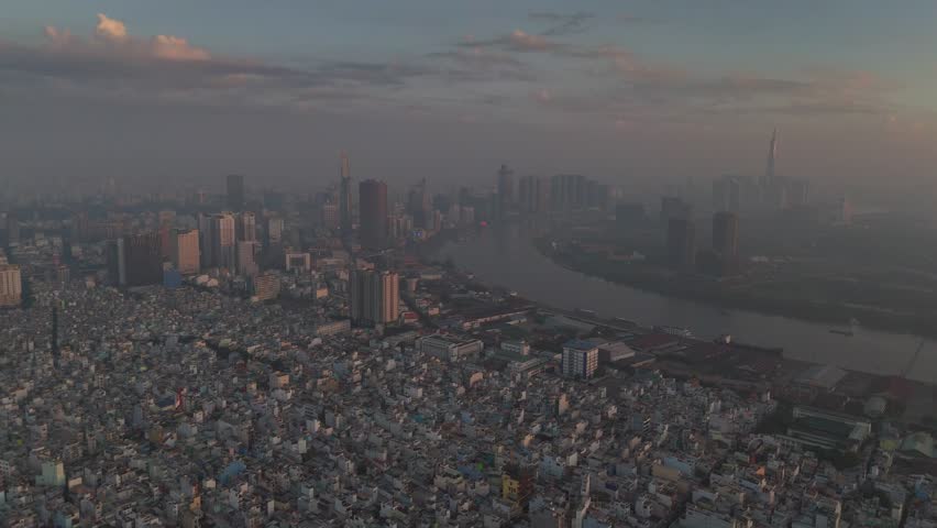 A series of drone clips capturing the winding Saigon River as it flows through the dense urban landscape of Ho Chi Minh City, Vietnam, at sunrise. The footage showcases the city's unique blend of natu