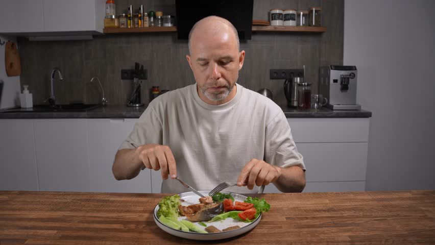Balanced mediterranean dinner for health. Middle-aged bald man eating at home kitchen.