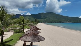 A series of drone clips capturing a beautiful sandy beach at Amiana Resort in Cam Ranh, Vietnam. The footage showcases rows of palm trees, lounge chairs, white umbrellas along the tranquil coastline - Powered by Shutterstock - Get 15% off with code: PIKWIZARD15