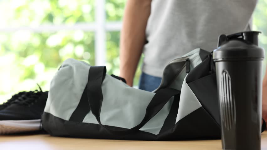Man packing his sports bag for training at home, closeup