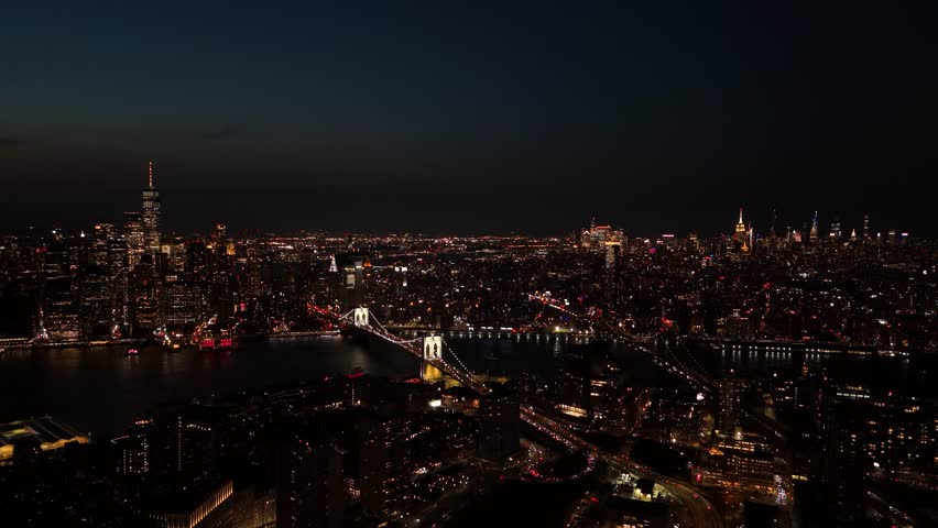 Aerial view of the city lights twinkling on skyscrapers and bridges at night, creating a dazzling and vibrant scene, Lower Manhattan, New York, United States.