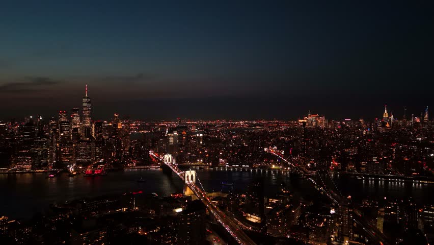 Aerial view of Manhattan Bridge and city lights twinkling against the dark sky, creating a mesmerizing contrast of light and shadow, Lower Manhattan, New York, United States.