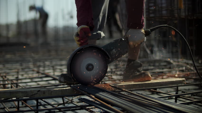 Worker cutting steel rebar with angle grinder