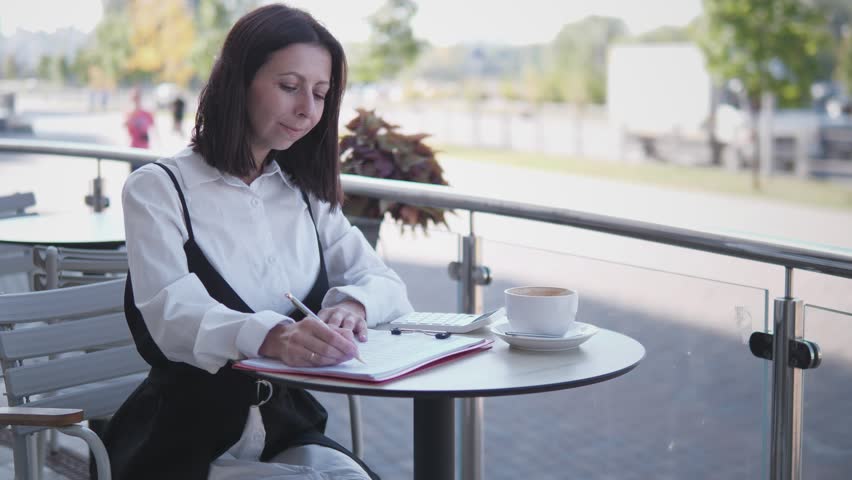 A beautiful woman checks the financial report in a summer cafe - Powered by Shutterstock - Get 15% off with code: PIKWIZARD15