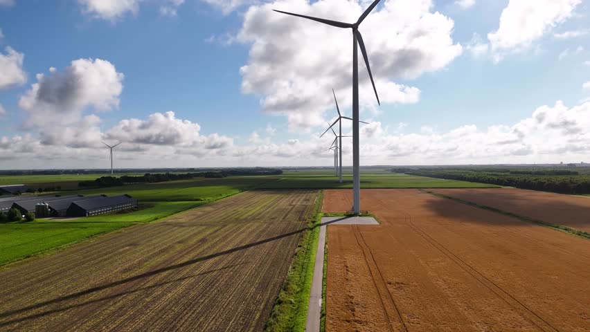 Wind turbines rotating in agricultural landscape under cloudy sky