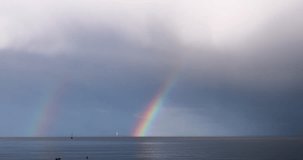 Double rainbow over water in real time. The arcs drift as rain curtains move across the scene. Secondary arc visible. 30 fps, no people. - Powered by Shutterstock - Get 15% off with code: PIKWIZARD15
