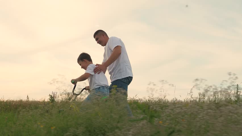 man father teaches boy son ride bike, schoolboy boy playing happily dad park, father running after bike child green meadow, happy family outdoors, children dream, adrenaline fast cycling, childhood