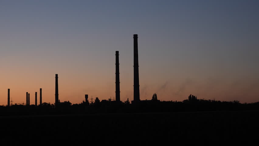 Silhouette of old factory chimneys at sunset. Abandoned industrial plant ruins with tall smokestacks against colorful evening sky. - Powered by Shutterstock - Get 15% off with code: PIKWIZARD15