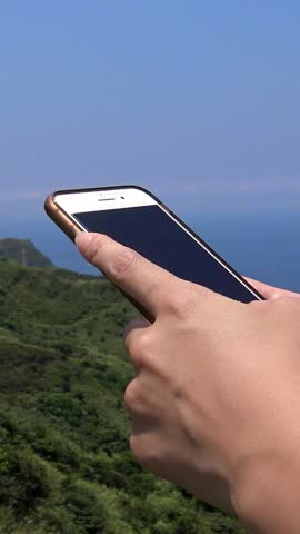 Close up asian hands woman using a smartphone in beutiful mountain with ocean background at Keelung. Girl tourist travel with phone device for surfing internet, checks social network in Taiwan