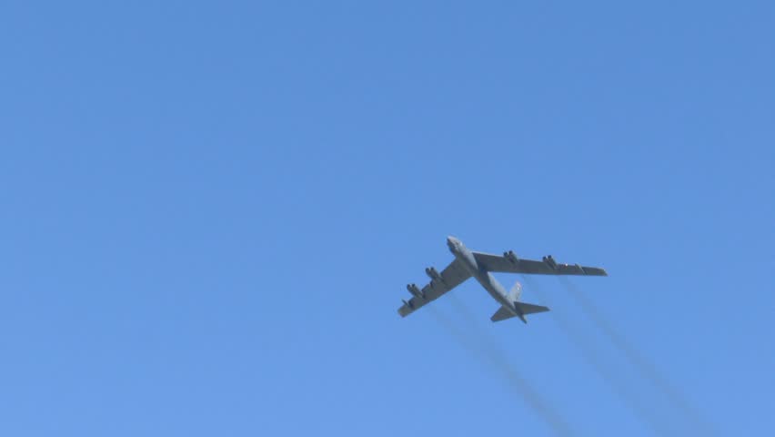 A B-52 strategic bomber flying overhead, trailing black smoke