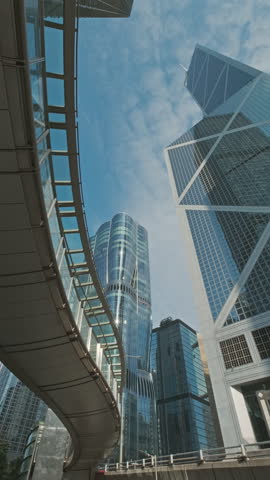 Modern skyscrapers reflect city skyline in bright daylight with clear blue sky above in an urban environment, Hong Kong. Vertical video 4k