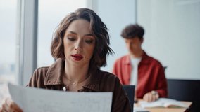 Woman checking documents with colleague in office closeup. Two coworkers discussing report working together at panoramic cabinet. Professional business team collaborating on project at open space - Powered by Shutterstock - Get 15% off with code: PIKWIZARD15