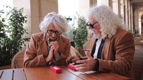 A lovely elderly couple shares a special moment as they excitedly unwrap a charming gift, highlighting their affectionate bond and joy in this delightful interaction filled with laughter and surprise - Powered by Shutterstock - Get 15% off with code: PIKWIZARD15