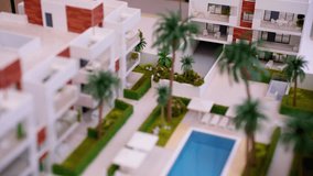 Detailed architectural scale model of a contemporary apartment complex featuring a swimming pool, green spaces with palm trees, and modern building design for a new housing development project - Powered by Shutterstock - Get 15% off with code: PIKWIZARD15