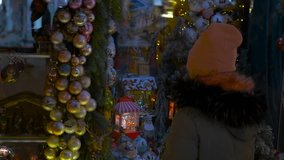 Girl admiring christmas decorations in a shop window. Enchanting holiday moment capturing young girl gazing at illuminated shop window, surrounded by golden baubles during festive winter evening - Powered by Shutterstock - Get 15% off with code: PIKWIZARD15