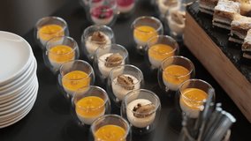 slow-motion video shows a dessert buffet table filled with assorted sweets, including layered chocolate cakes, colorful macarons, mini tarts, cream puffs, and elegant glass cups of mousse, panna cotta - Powered by Shutterstock - Get 15% off with code: PIKWIZARD15
