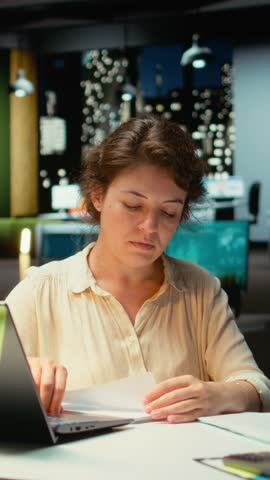 Vertical Video Livid businesswoman breaking a paper page after making a mistake, handwriting and notetaking in office after hours. Displeased impatient worker redoing the draft on a new sheet. Camera