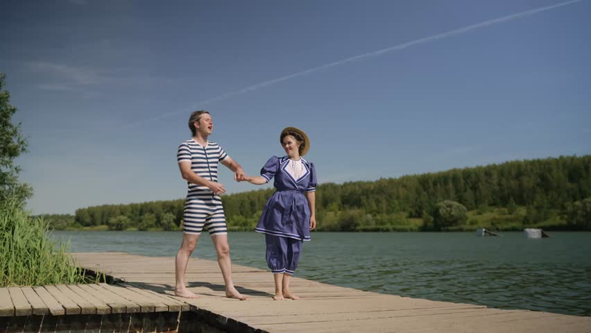 Couple walking on dock wearing retro swimsuits. A girl and a guy in a Soviet-era swimsuit.