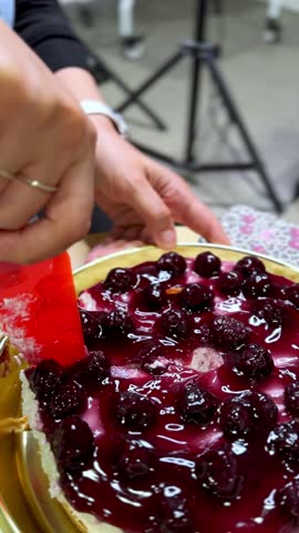 Close-up vertical video of a hand wearing a smartwatch slicing into a blueberry cheesecake with a spoon. Perfect for food reels, recipe shorts, dessert ads, lifestyle content, and social media .