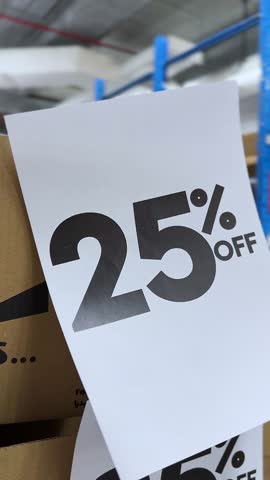 Close-up vertical video of a 25% OFF discount sale sign on cardboard in a warehouse store. Ideal for e-commerce, seasonal sales, retail promotions, TikTok ads, Instagram Reels, and digital marketing.