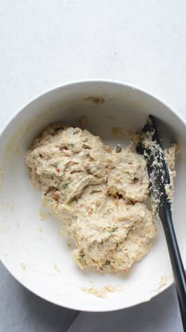 overhead view of savory biscotti dough being mixed in a bowl, top view of savory cookie dough in a mixing bowl
