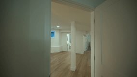 Renovated basement room with light wooden flooring, smooth white walls, and recessed ceiling lights creating a contemporary living space. Camera move in - Powered by Shutterstock - Get 15% off with code: PIKWIZARD15