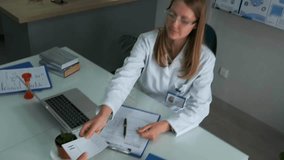 Female doctor in white coat sitting at desk with laptop and medical documents, consulting older male patient and handing prescription. Professional healthcare scene in clinic. - Powered by Shutterstock - Get 15% off with code: PIKWIZARD15