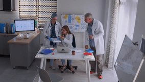 Group of three doctors in clinic office studies printed medical data and charts, collaborating in diagnosis and treatment discussion. Healthcare professionals analyzing patient information. - Powered by Shutterstock - Get 15% off with code: PIKWIZARD15