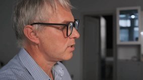 Close-up side profile of elderly man with gray hair and glasses, speaking about his symptoms. Senior patient portrait during medical consultation in clinic or hospital. - Powered by Shutterstock - Get 15% off with code: PIKWIZARD15
