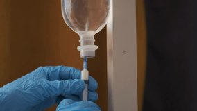 Gloved medical worker adjusting IV drip and filling syringe from infusion bottle. Close-up, nurse hands performing intravenous procedure in hospital environment. Professional healthcare treatment. - Powered by Shutterstock - Get 15% off with code: PIKWIZARD15