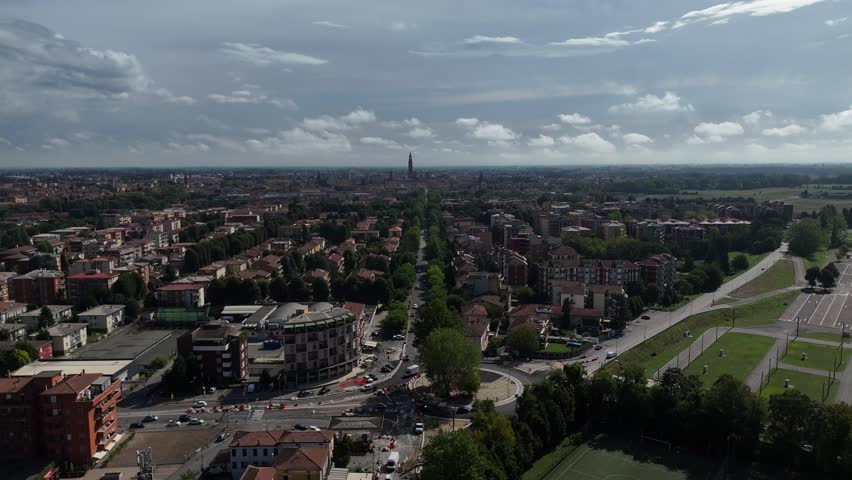Expansive Aerial View of a Long Tree Lined Boulevard with Buildings and Green Spaces in Cremona Italy Under a Cloudy Sky on a Summer Day