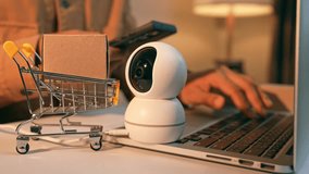 A businessman works intensely, holding a phone and typing on a laptop, with a product in a mini cart and a CCTV camera conveying sales-driven focus, e-commerce security, digital business efficiency.
 - Powered by Shutterstock - Get 15% off with code: PIKWIZARD15