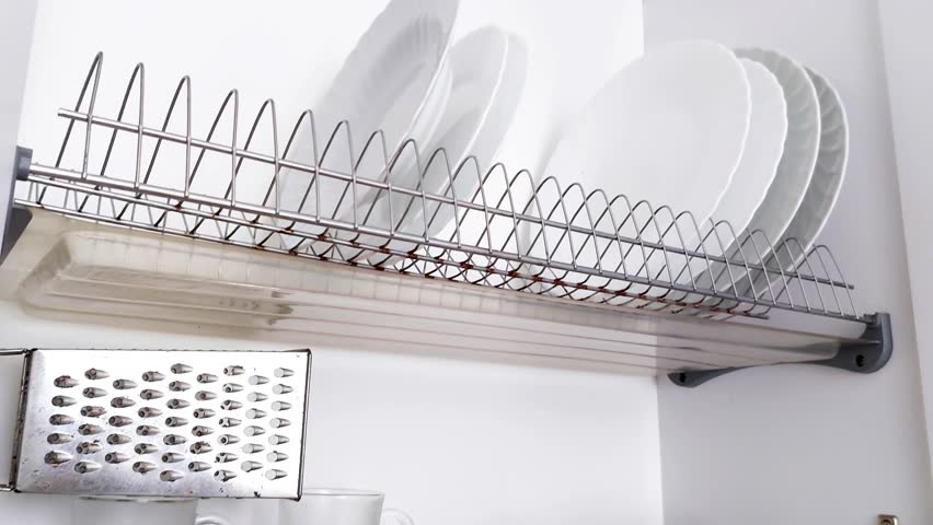 Tidy kitchen cabinet with neatly stacked plates, bowls, grater, and brush. Minimalist storage setup showcasing clean lines, organized shelves, and practical placement