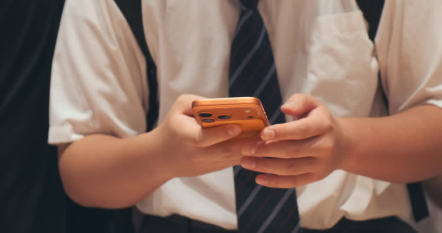 Close-up, man holding orange phone in electronics store. Customer testing, texting in new smartphone, showcasing modern technology, consumer lifestyle. Person using mobile phone gadget