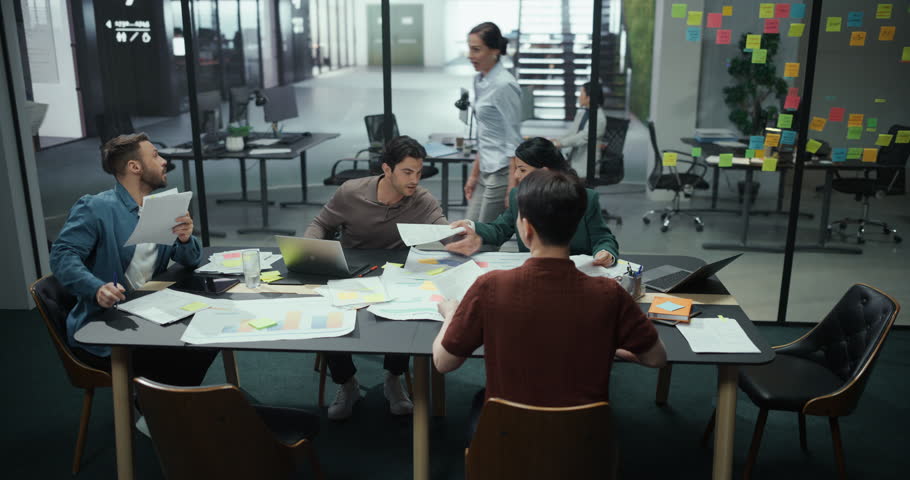 Excited Managers and Employees Having a Brainstorming Session in an Office Meeting Room. Male and Female Colleagues Share Ideas, Opinions, Looking at Documents and Discussing Reports