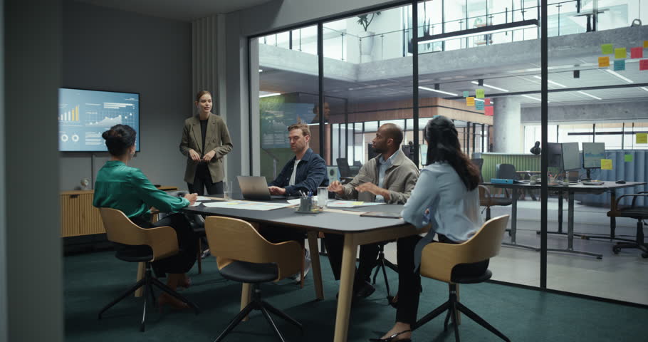 Corporate Keynote Presentation in Office Conference Hall. Caucasian Female Project Leader Explain Business Plans to a Mixed Group of Managers and Employees Focused on Speaker and Slides
