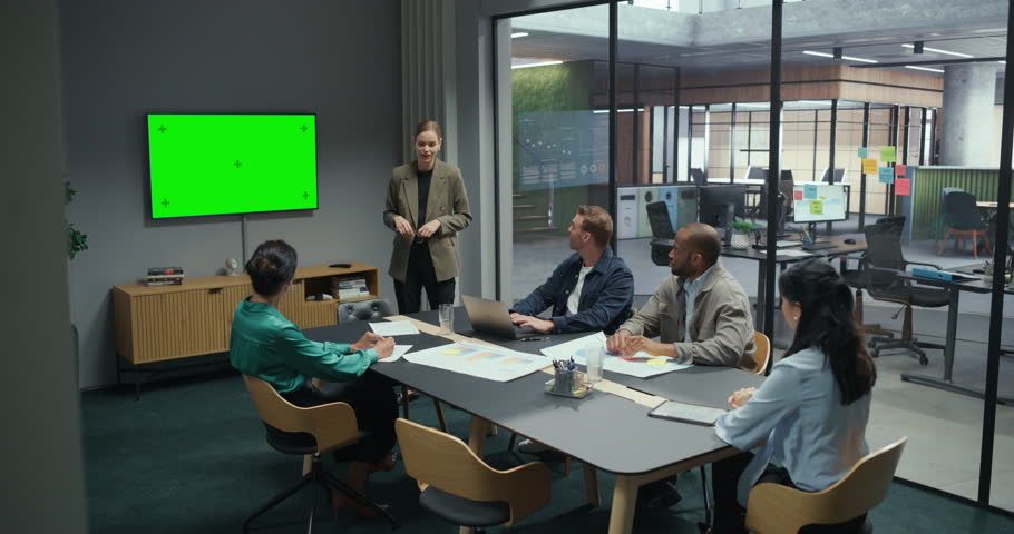 Corporate Presentation in Office Conference Hall with a Green Screen Chroma Key Display. Female Project Leader Explain Business Plans to a Group of Managers and Employees Focused on a Speaker