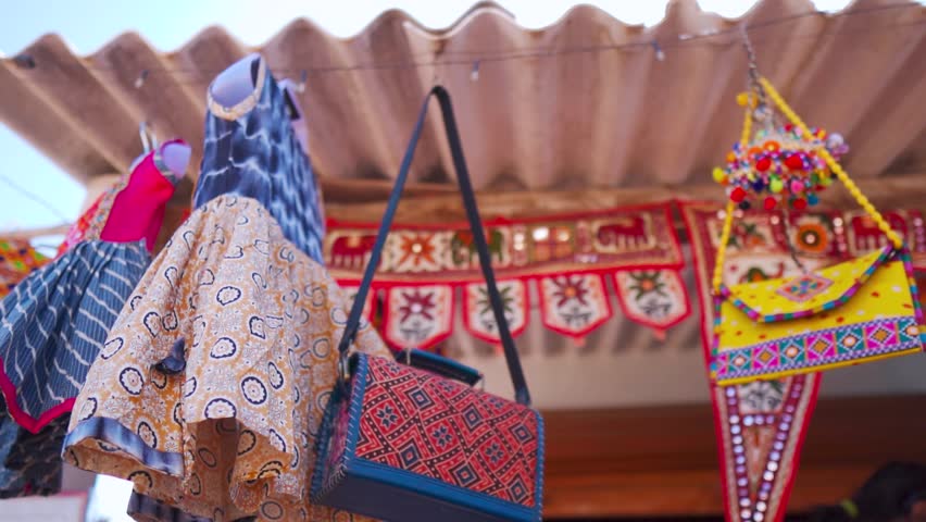 Kutchi Handicraft items hanging on local market at Rannutsav in Kutch, Gujarat, India. Handmade purse and clothes in street shop. Kutchi Handicraft arctician designer cloth 