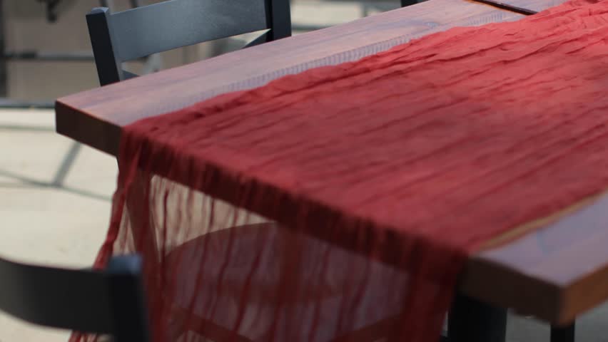 Planner tying a knot at the end of a table runner for an outdoor dinner.