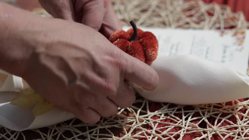 Planner setting a napkin on a placemat for an outdoor dinner.
