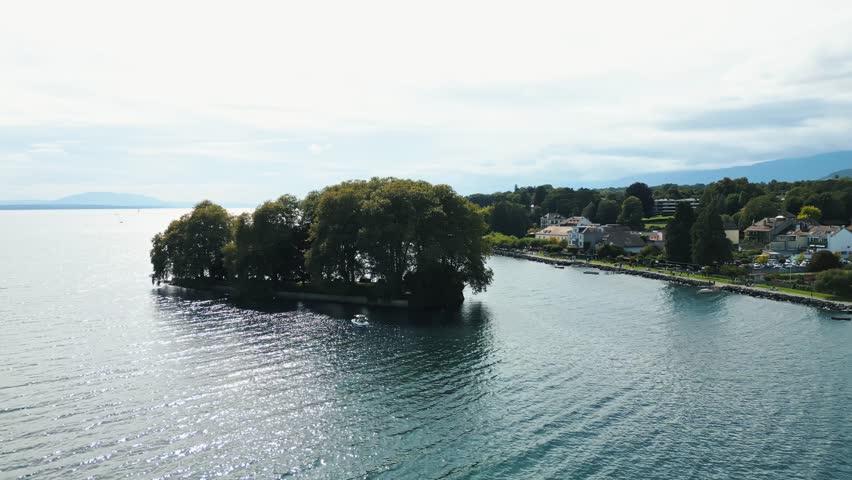 Aerial view of Ile de la Harpe islet, a verdant island, surrounded by the blue waters of Lake Geneva, near Rolle, Vaud, Switzerland.